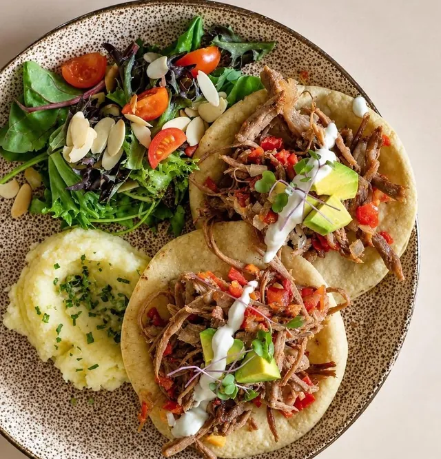 Plato del menú diario: carne deshebrada sobre tortilla, puré de papa y ensalada con almendra